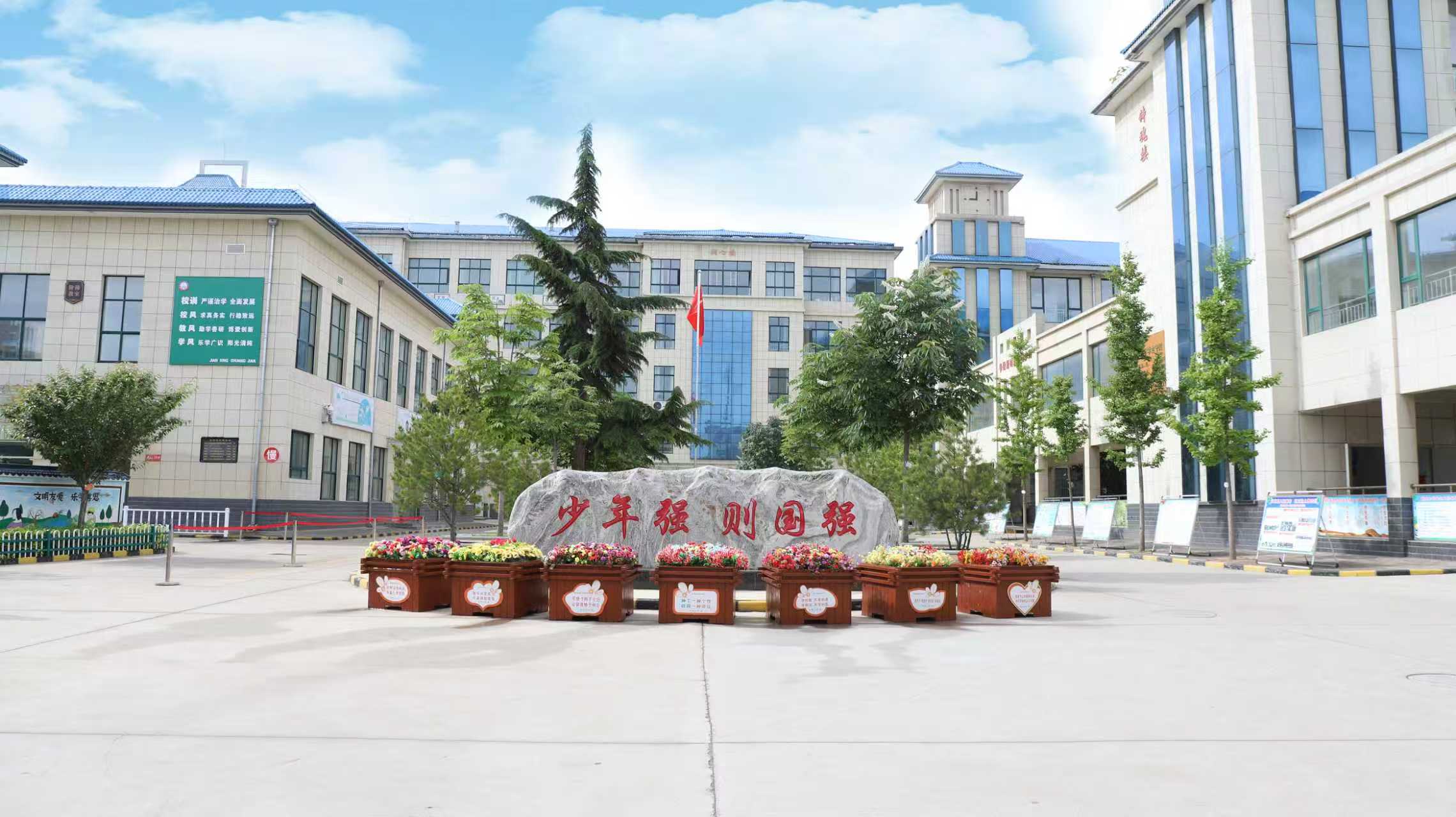 庆阳市西峰区新建小学建筑外观，现代化教学楼群，绿树环绕，阳光明媚
